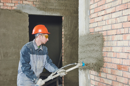 Plasterer spraying plaster on wall